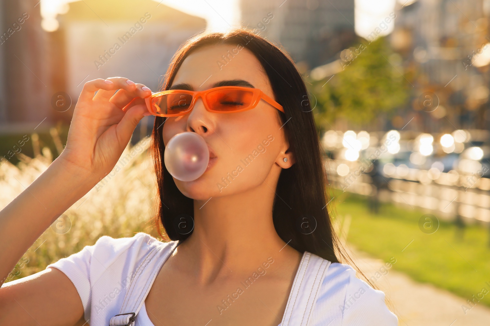 Photo of Beautiful woman in sunglasses blowing gum outdoors