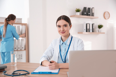 Photo of Portrait of female doctor at table in modern clinic