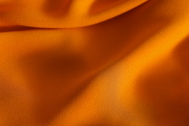 Photo of Texture of orange crumpled fabric as background, closeup view