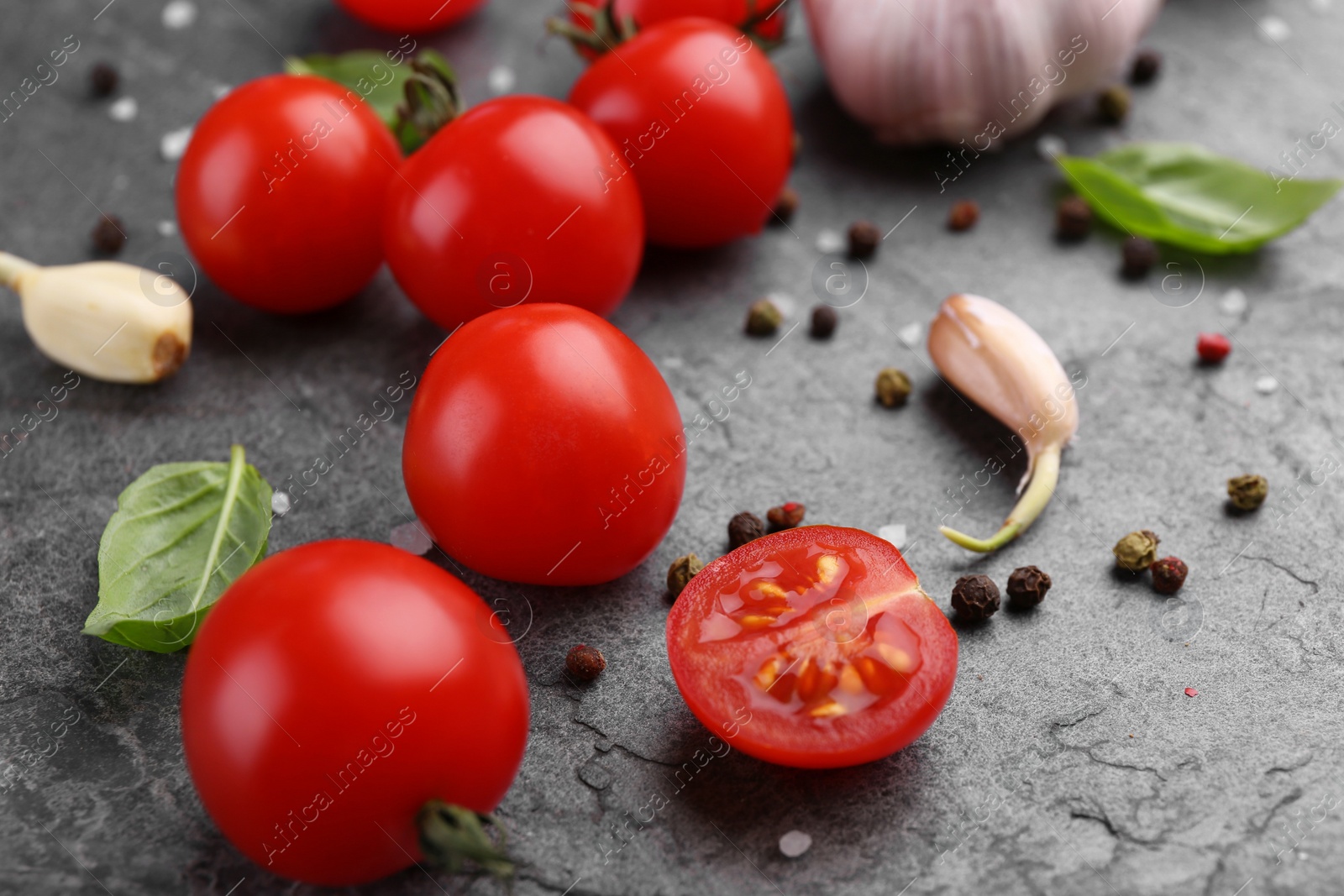 Photo of Ripe tomatoes, basil, garlic and spices on gray textured table, closeup