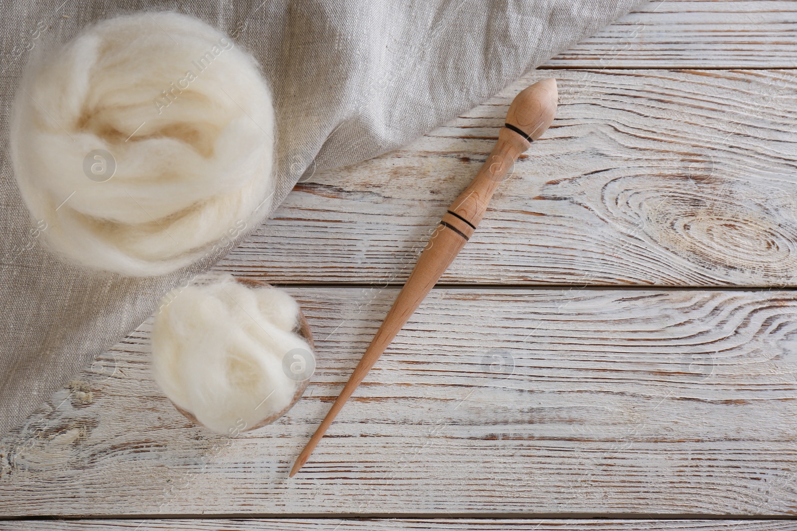 Photo of Soft wool and spindle on white wooden table, flat lay. Space for text