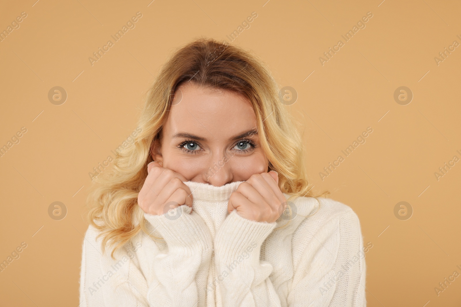 Photo of Beautiful woman in stylish warm sweater on beige background