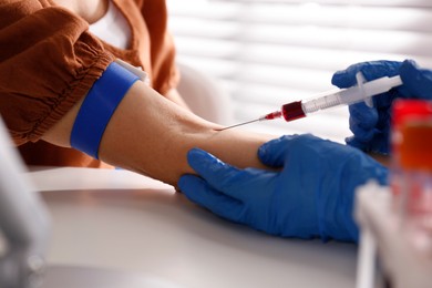 Photo of Nurse drawing blood sample from patient in clinic, closeup