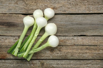 Photo of Whole green spring onions on wooden table, flat lay. Space for text