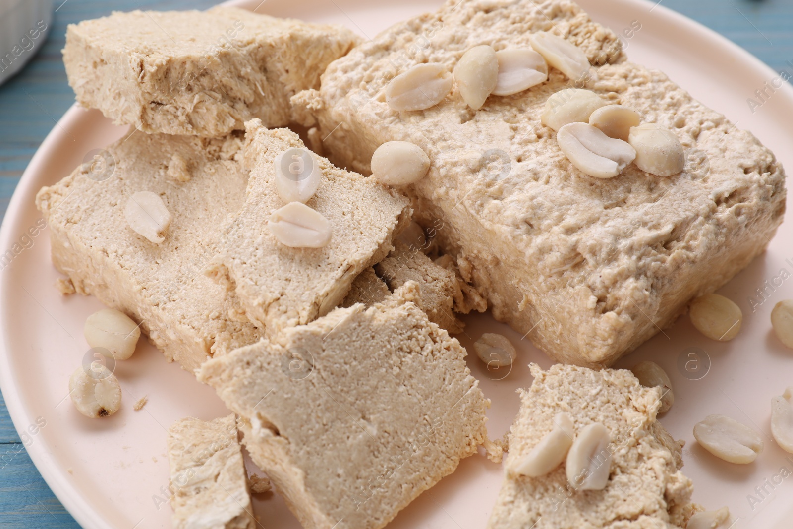 Photo of Pieces of tasty halva and peanuts on plate, closeup