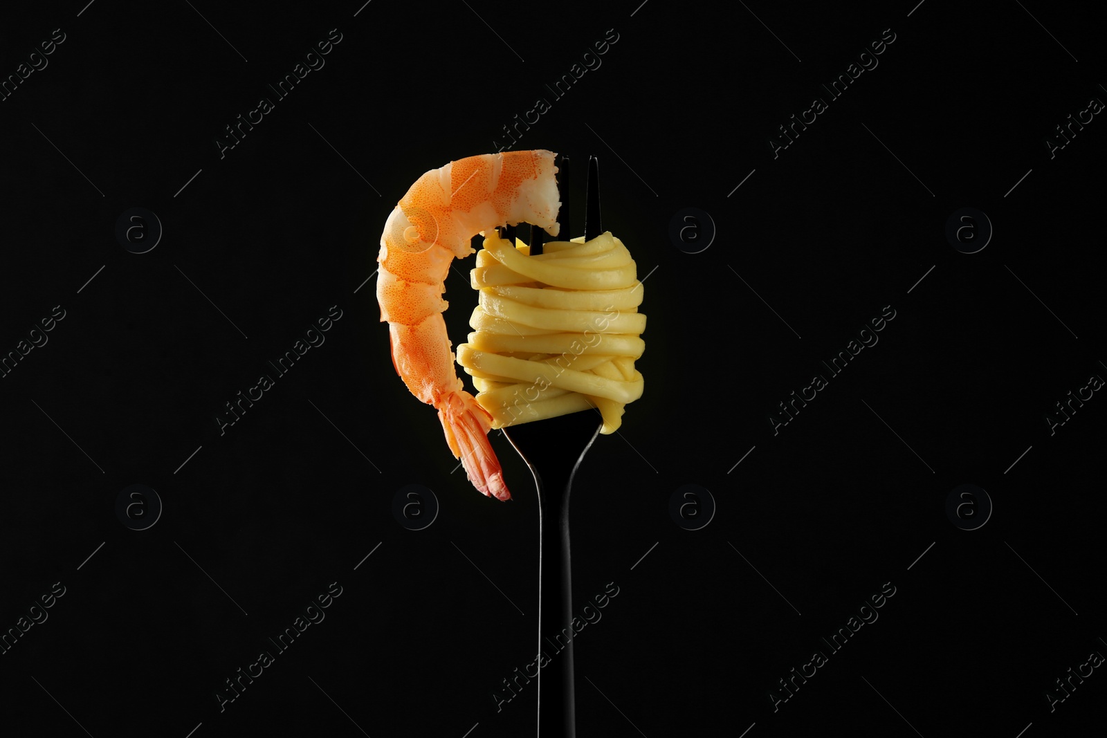 Photo of Fork with tasty pasta and shrimp on black background