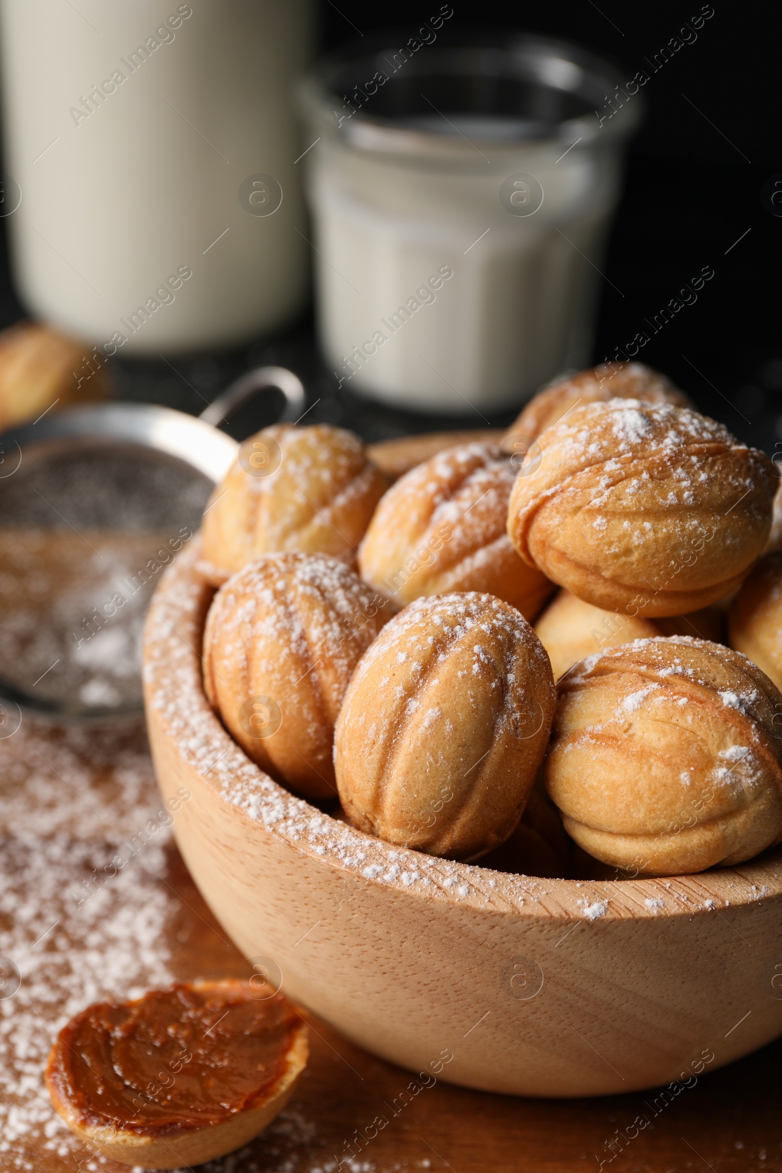 Photo of Delicious nut shaped cookies with powdered sugar on wooden table, closeup. Space for text