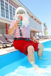 Authentic Santa Claus with cocktail near pool at resort