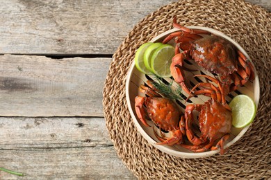 Delicious boiled crabs with lime and dill in bamboo steamer on wooden table, top view. Space for text
