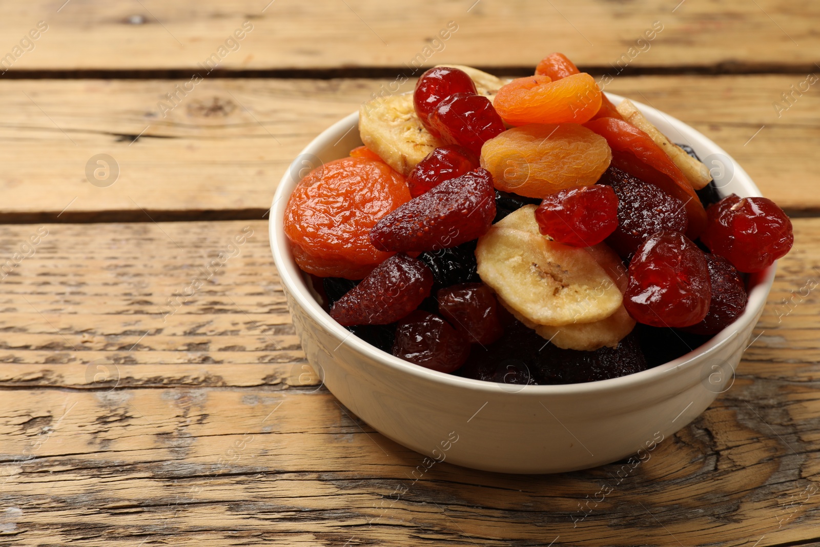 Photo of Mix of delicious dried fruits on wooden table, closeup. Space for text