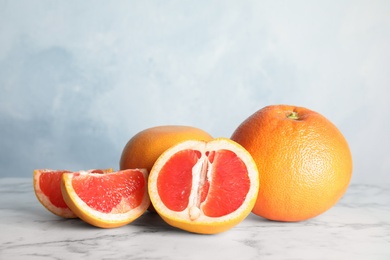 Photo of Fresh tasty grapefruits on table against color background