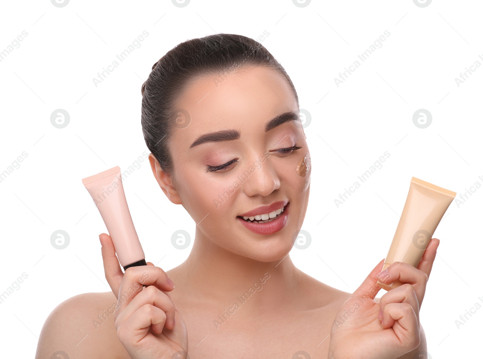 Photo of Woman holding tubes of foundation on white background