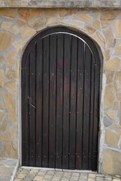 Entrance of building with beautiful arched wooden door in stone wall outdoors