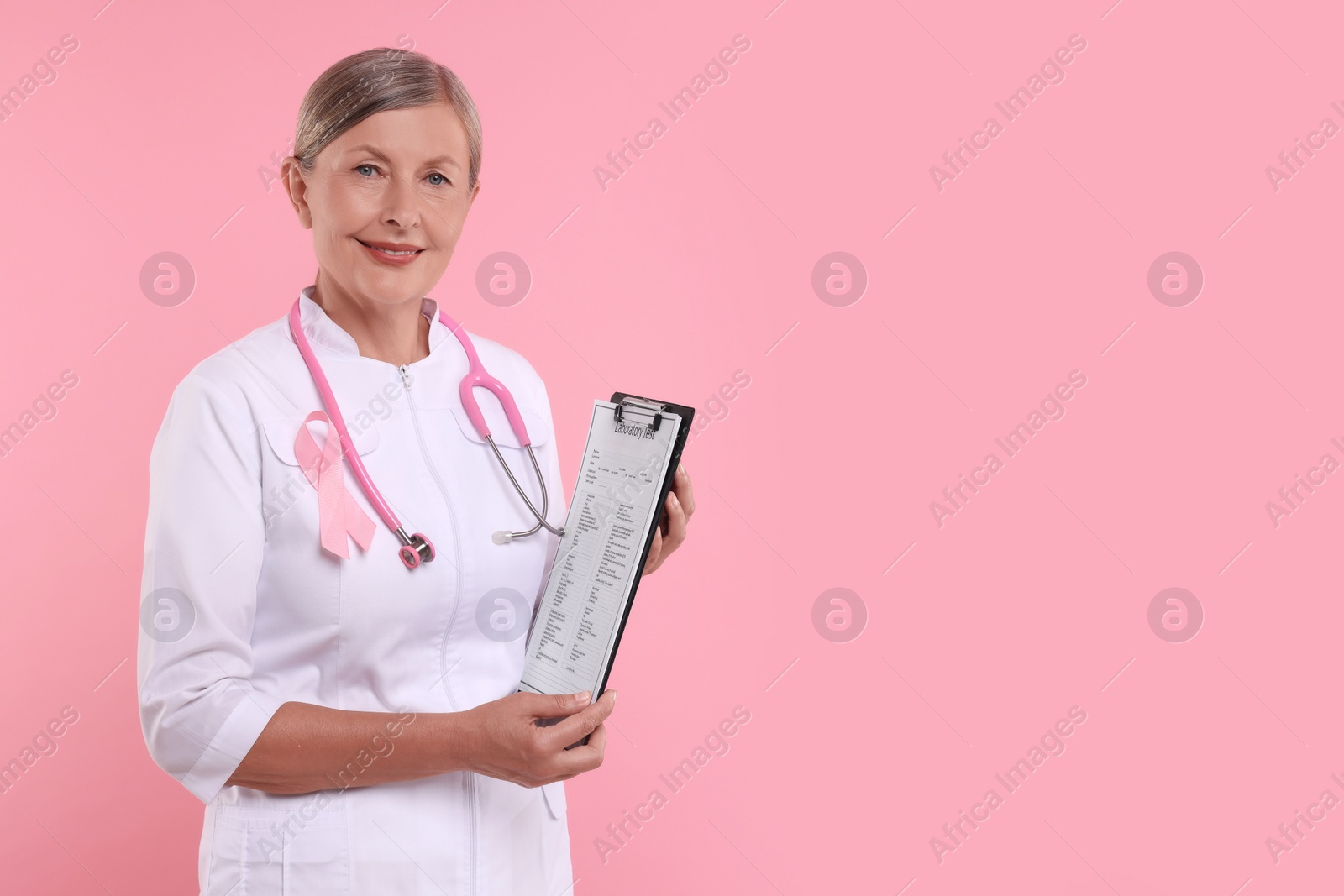 Photo of Doctor with pink ribbon, clipboard and stethoscope on color background, space for text. Breast cancer awareness