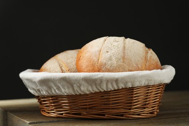 Photo of Wicker basket with fresh bread on wooden table