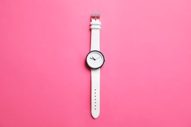 Photo of Stylish wrist watch on color background, top view. Fashion accessory