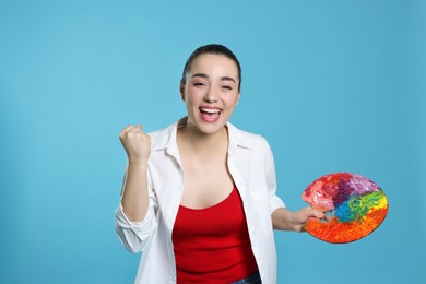 Photo of Woman with paint palette on light blue background. Young artist