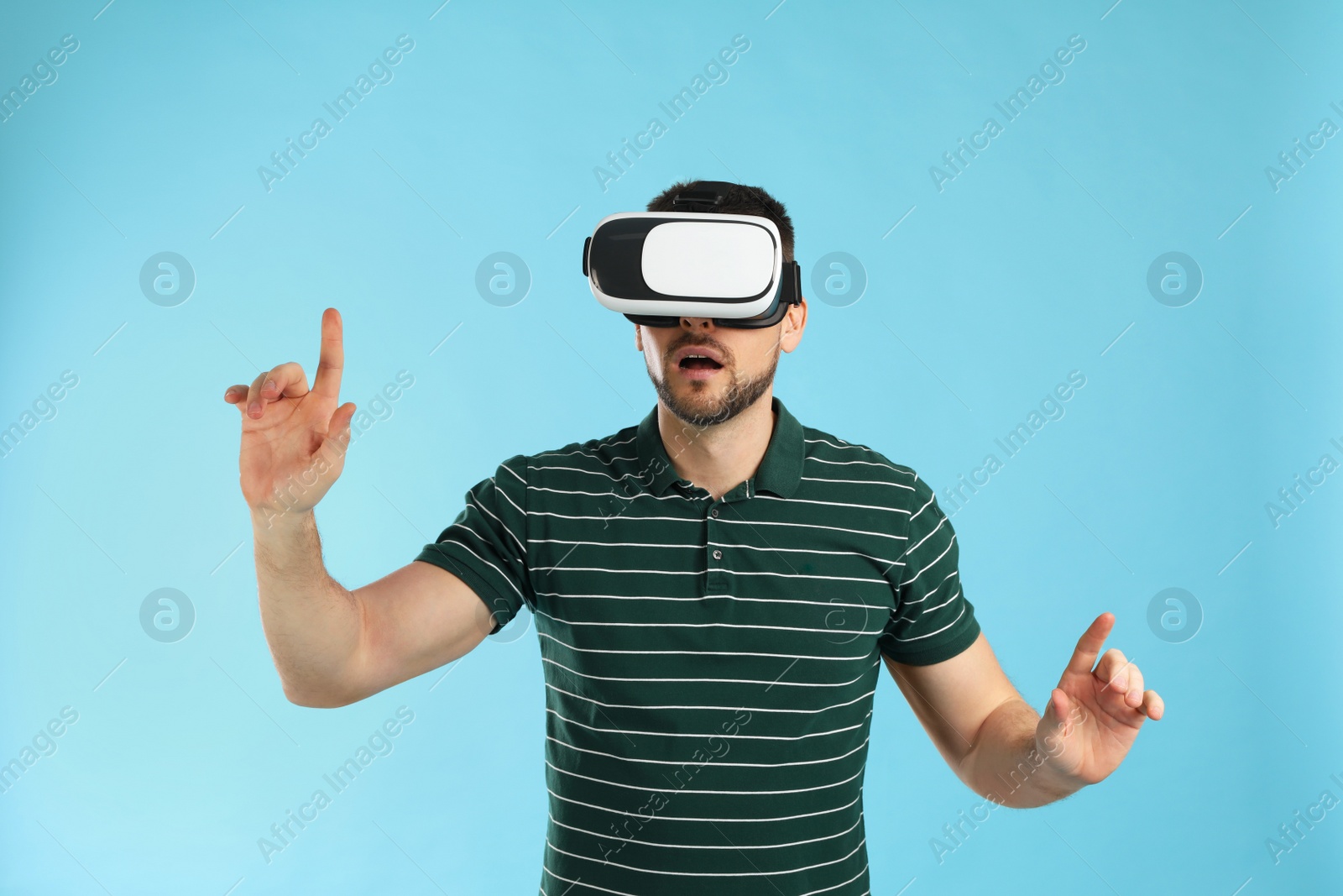 Photo of Man using virtual reality headset on light blue background