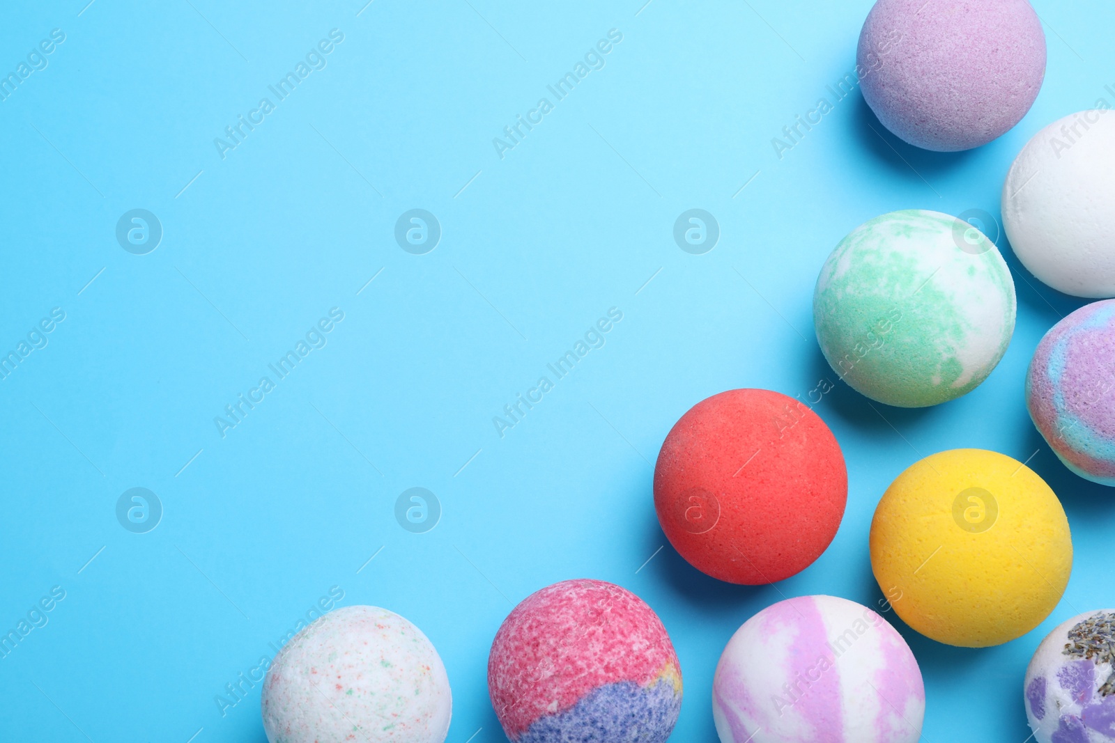 Photo of Colorful bath bombs on light blue background, flat lay. Space for text