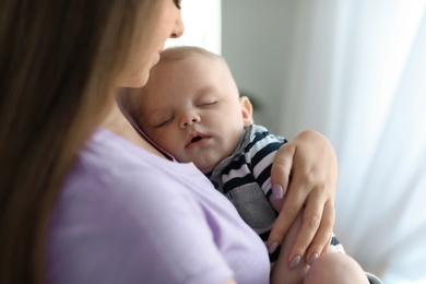 Photo of Mother with her sleeping baby at home, closeup view