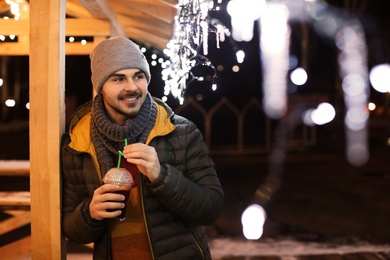 Photo of Man with cup of mulled wine at winter fair. Space for text