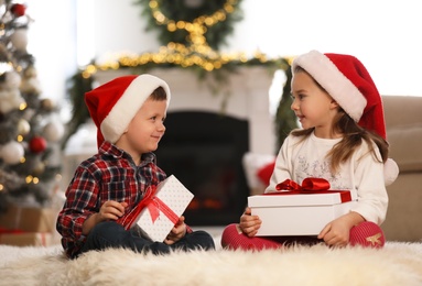 Photo of Cute children holding gift boxes in room decorated for Christmas