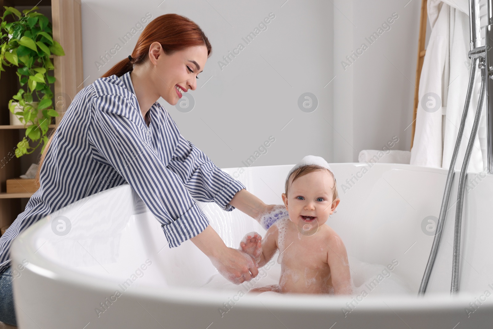 Photo of Mother washing her little baby in tub at home