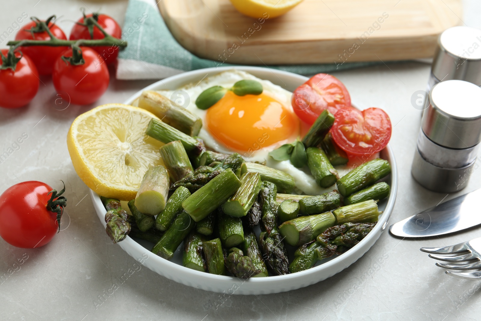 Photo of Oven baked asparagus served with fried egg on light grey marble table