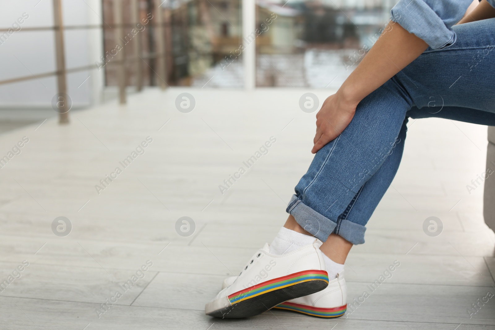 Photo of Young woman suffering from leg pain indoors, closeup with space for text