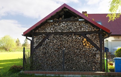 Shed with stacked firewood outdoors on sunny day