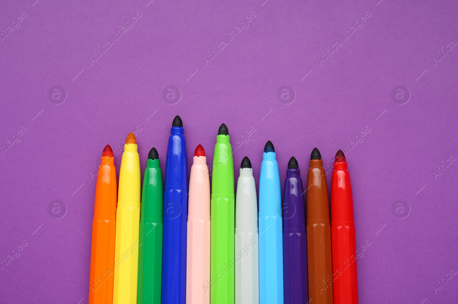 Photo of Different colorful markers on purple background, flat lay. Space for text