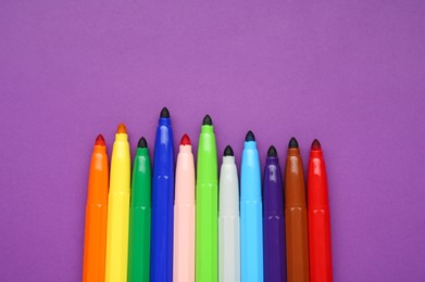 Photo of Different colorful markers on purple background, flat lay. Space for text