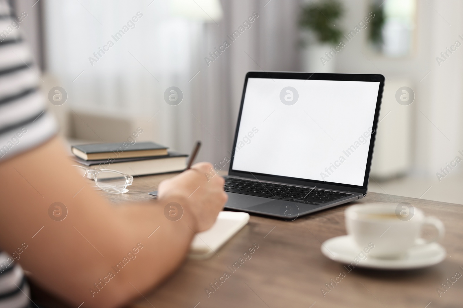 Photo of Young man writing down notes during webinar at table in room, closeup