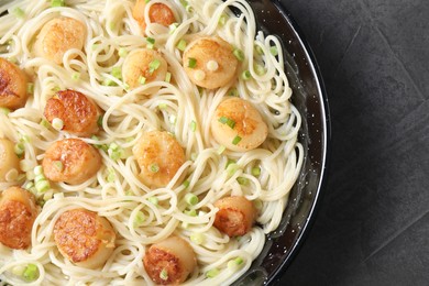 Photo of Delicious scallop pasta with green onion on grey table, top view
