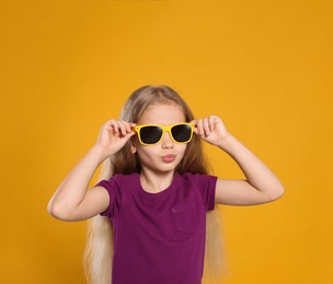 Photo of Girl in stylish sunglasses on orange background