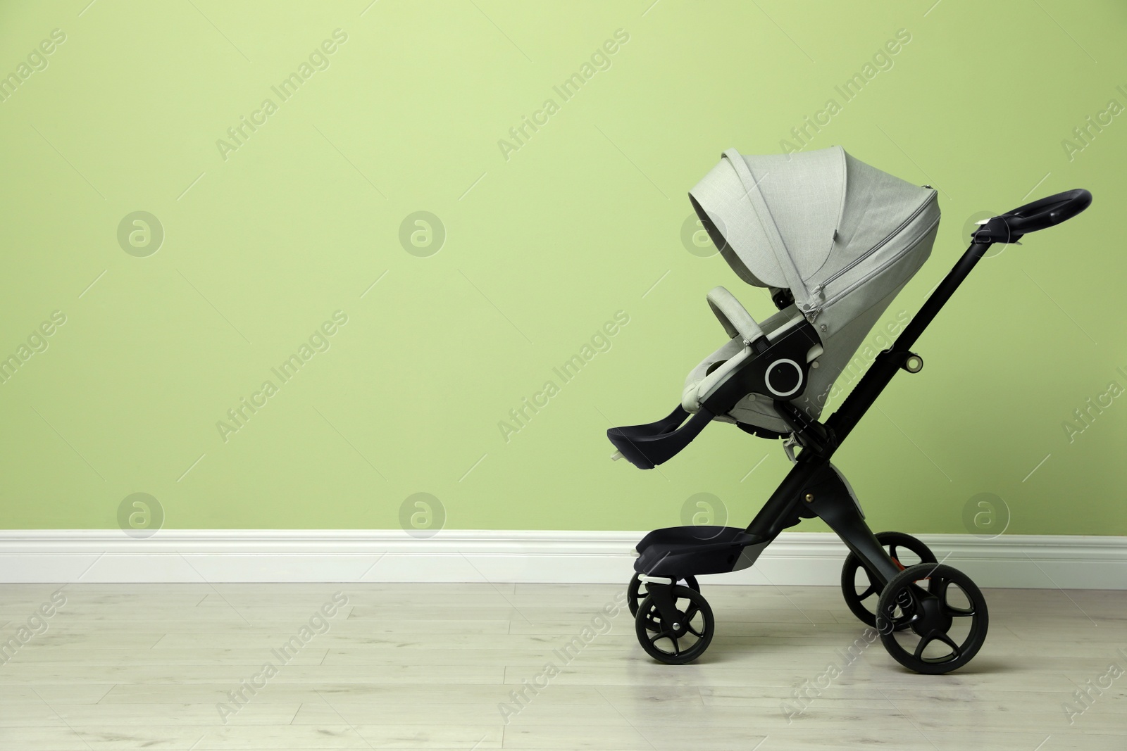 Photo of Baby carriage. Modern pram near light green wall, space for text