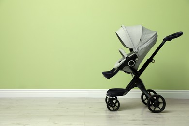 Photo of Baby carriage. Modern pram near light green wall, space for text