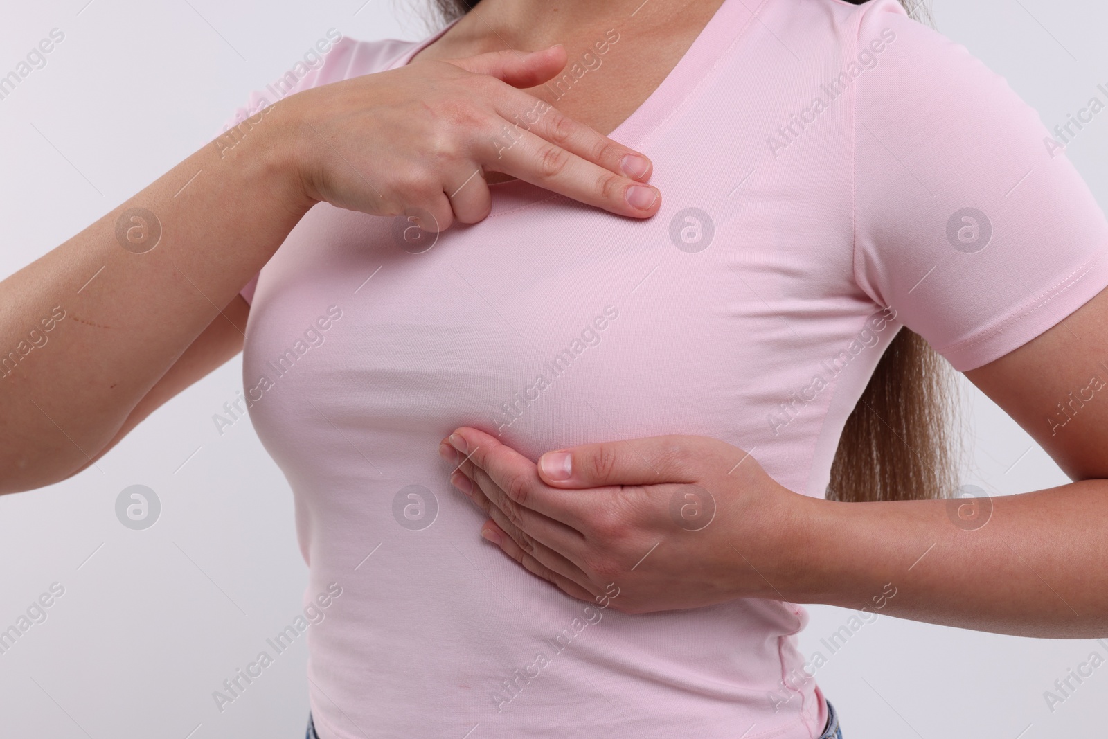 Photo of Woman doing breast self-examination on white background, closeup