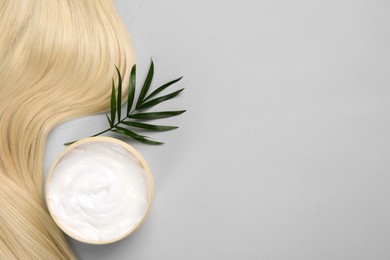 Photo of Lock of healthy blond hair, cosmetic product and green twig on light grey background, flat lay. Space for text