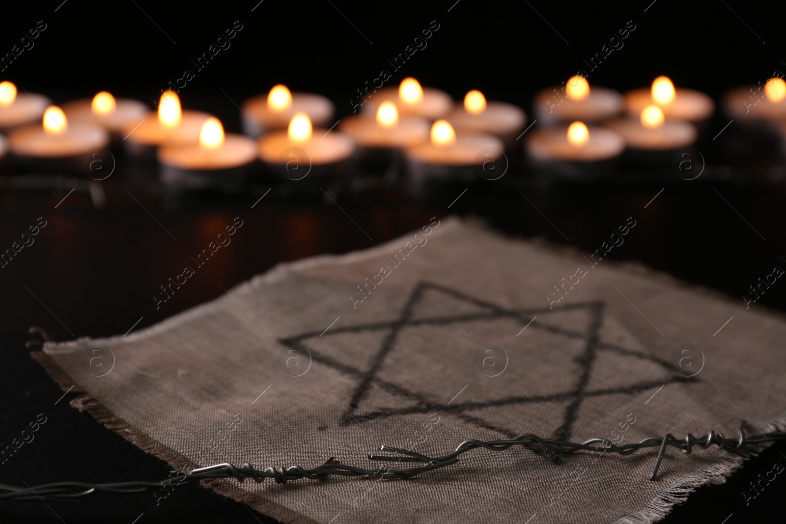 Photo of Fabric with star of David and barbed wire on black background. Holocaust memory day
