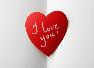 Paper heart with words I LOVE YOU on open notebook, top view