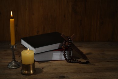 Photo of Church candles, Bible, cross and rosary beads on wooden table