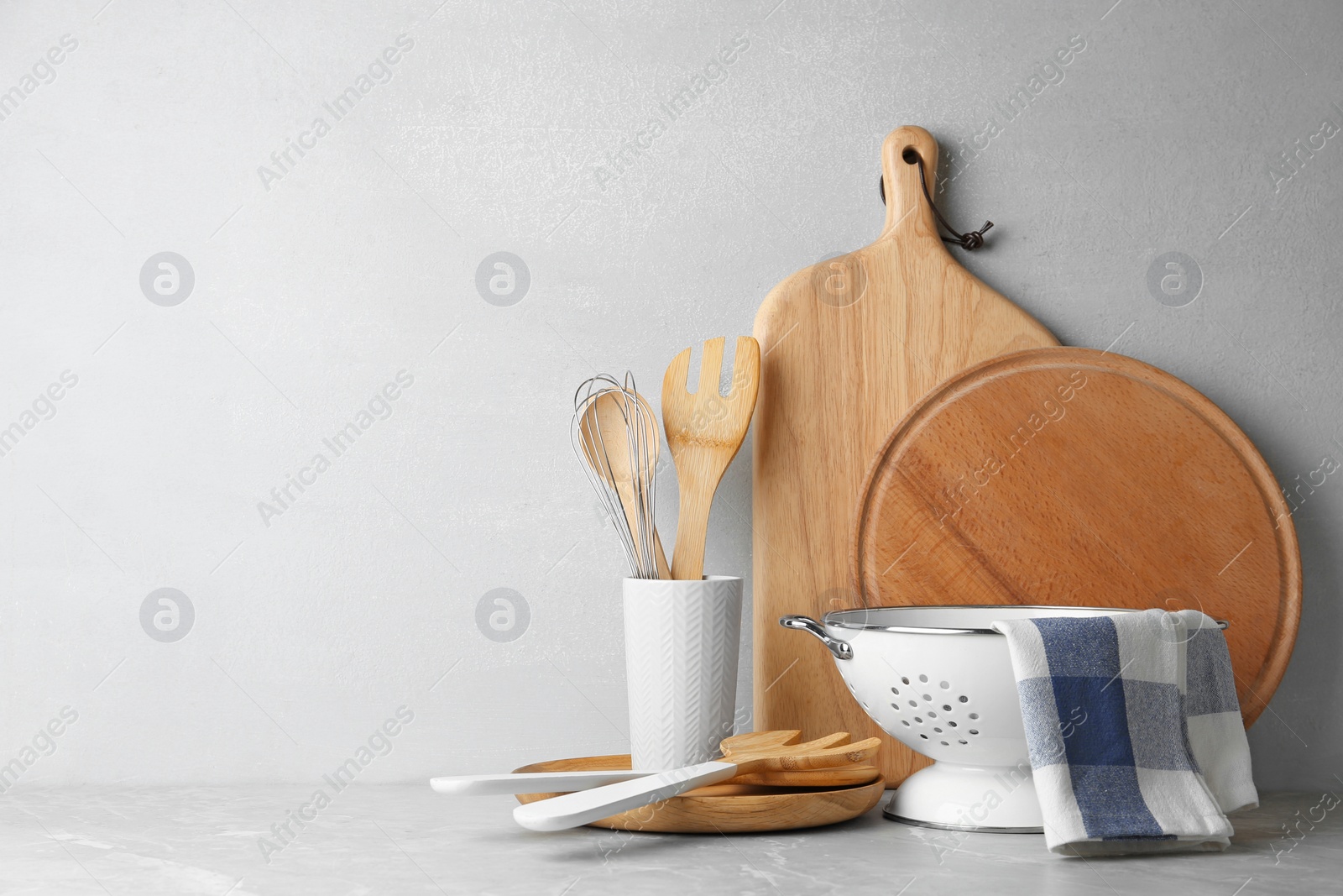 Photo of Different kitchen utensils on table against light background. Space for text