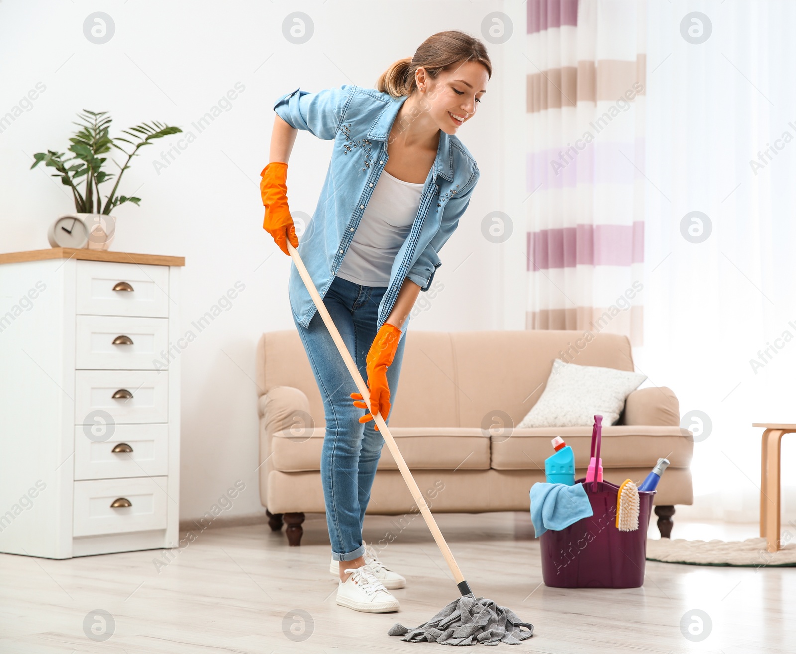 Photo of Young woman washing floor with mop in living room. Cleaning service