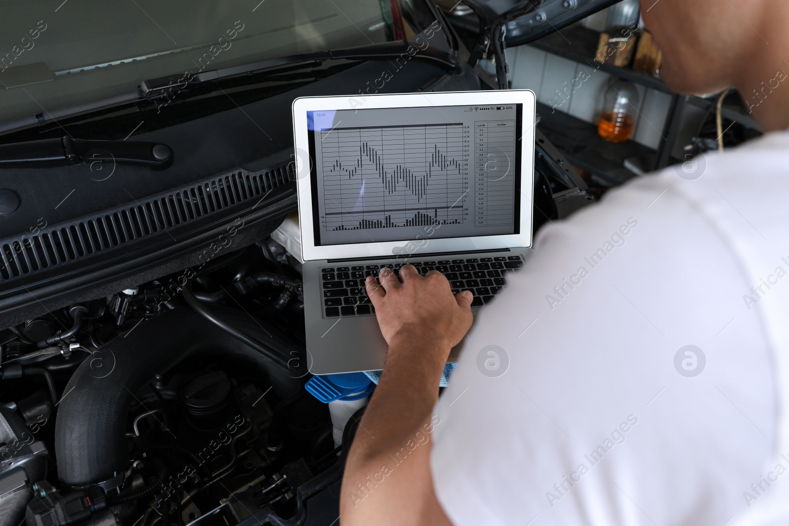 Photo of Mechanic with laptop doing car diagnostic at automobile repair shop, closeup