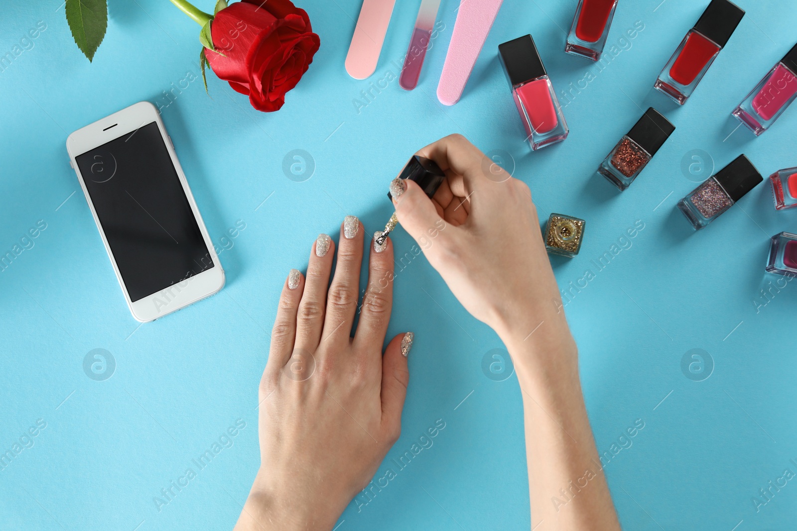 Photo of Woman applying nail polish on color background, top view