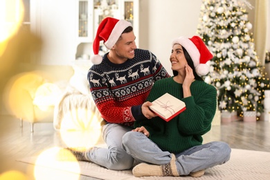 Man presenting Christmas gift to his girlfriend at home