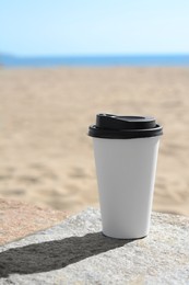 Takeaway coffee cup on beach, space for text