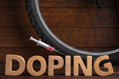 Photo of Word Doping, syringe and bicycle wheel on wooden background