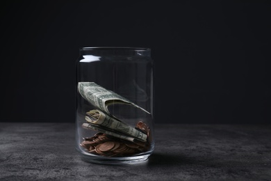 Photo of Donation jar with money on table against dark background. Space for text